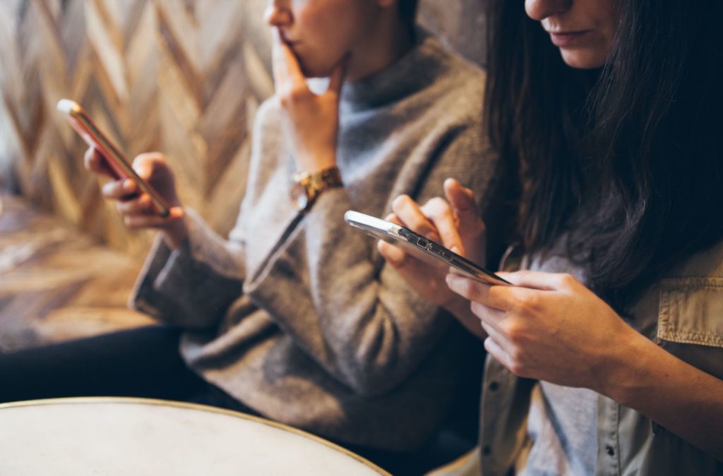 Two women concentrating on mobile phones in hand