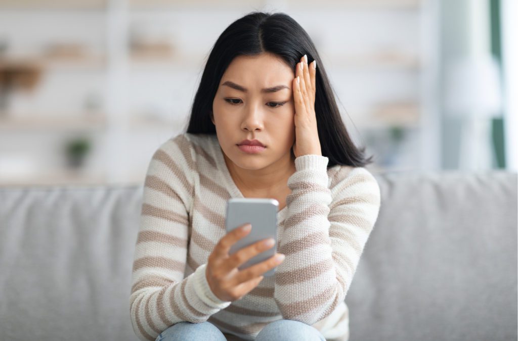 Person looking conflicted while using mobile device